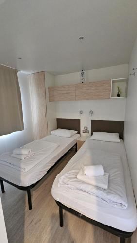 deux lits dans une chambre avec des draps blancs dans l'établissement Mobilna kućica Tara, uvala Slanica, Murter, à Murter