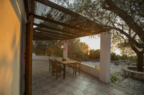 a patio with a table and chairs under a pergola at Nereidi Villas in Porto Ozias