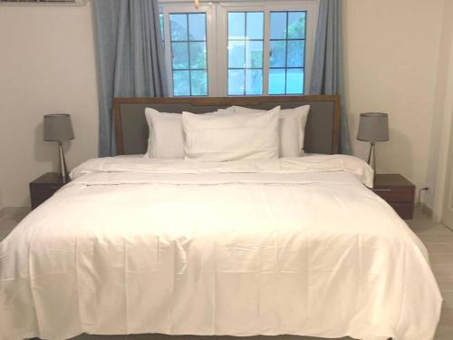 a white bed with white sheets and pillows at Suites Pineapple in Rock Sound