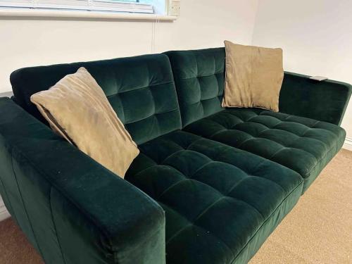 a green leather couch with two pillows on it at East London Apartment near Station & Free Parking in Romford
