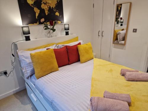 Una cama con almohadas amarillas y rojas. en Luxury Modern Apartment Stay en Sheffield