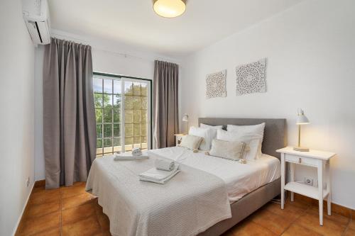 een slaapkamer met een groot wit bed en een raam bij Vilamoura - Cozy and Quiet Holiday Apartment in Vilamoura
