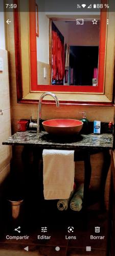 a bathroom counter with a red sink and a mirror at Alonso Chacras Lodge in Chacras de Coria