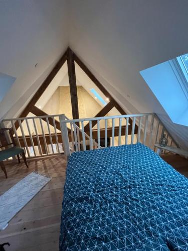 um quarto com uma cama azul no sótão em Gite à la Ferme pédagogique Les petits sabots de L'oudon em Bretteville-sur-Dives