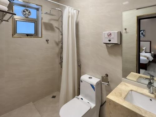 La salle de bains est pourvue de toilettes, d'un lavabo et d'une douche. dans l'établissement Daar AL Maqam Suites Apartments Salalah, à Salalah