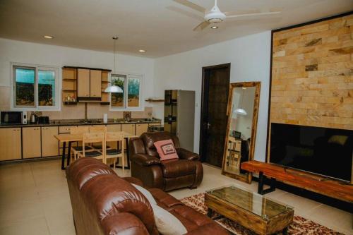 a living room with a leather couch and a kitchen at Jwapano housing in Dar es Salaam