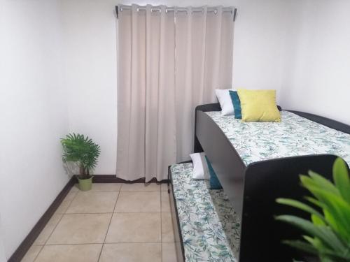 Habitación pequeña con cama y ventana en Kubo Home 4 Bedrooms 5 mins SJO Airport en Alajuela