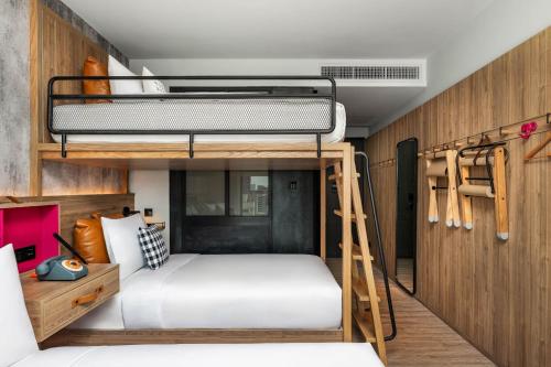 a bunk bed in a room with a ladder and a bunk bed in a bedroom at Moxy Bangkok Ratchaprasong in Bangkok