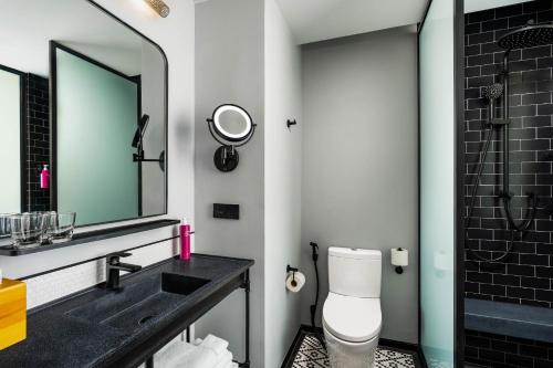 a bathroom with a sink and a toilet and a mirror at Moxy Bangkok Ratchaprasong in Bangkok