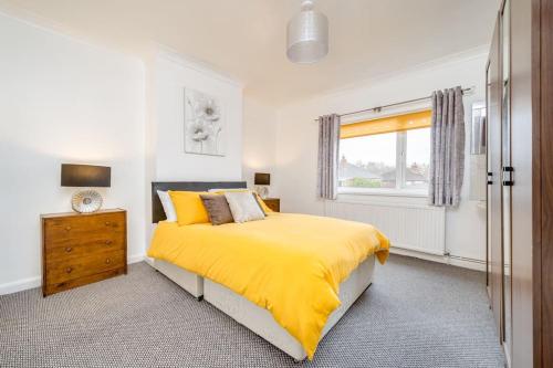 a bedroom with a yellow bed and a window at Contemporary 5 Bedroom Flat in Killingbeck