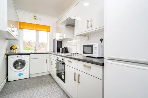 a kitchen with white cabinets and a washer and dryer at Contemporary 5 Bedroom Flat in Killingbeck