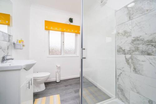 a white bathroom with a shower and a toilet at Contemporary 5 Bedroom Flat in Killingbeck