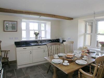 uma cozinha com uma mesa de madeira com cadeiras e um lavatório em Mouse Castle Barn em Hay-on-Wye