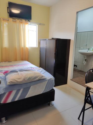 een slaapkamer met een bed, een wastafel en een spiegel bij Condominio confortable in Talara