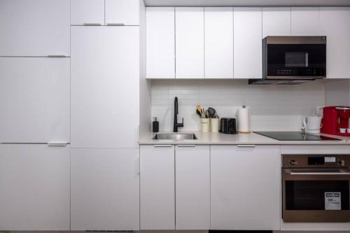 a white kitchen with a sink and a microwave at Furnished Studio with balcony - Downtown #311784 in Montreal