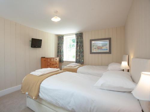 a bedroom with two beds and a tv on the wall at South Wing Cottage in Rumleigh