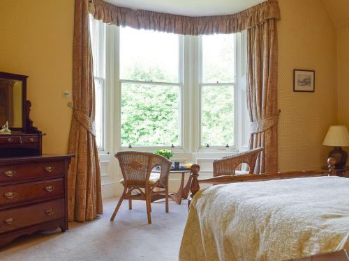 a bedroom with a bed and a large window at Creag-ard House in Aberfoyle