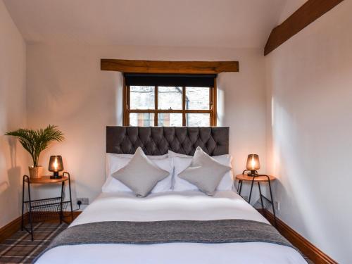 - une chambre avec un grand lit blanc et une fenêtre dans l'établissement Millside Cottage, à Natland