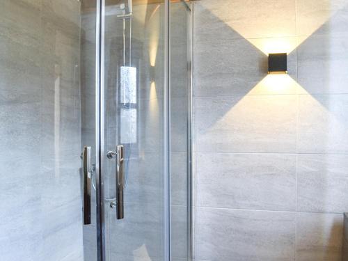 a shower with a glass door in a bathroom at Millside Cottage in Natland