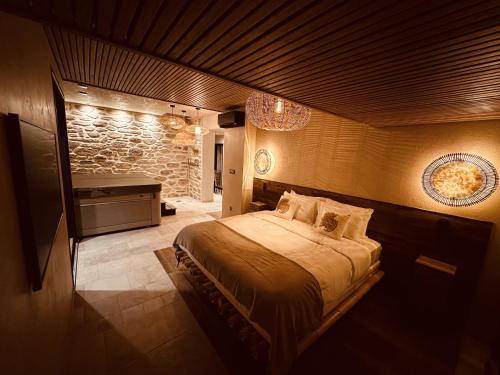 a bedroom with a bed and a stone wall at Suite Deluxe & Spa #Wabi-Sabi# in Bray-Dunes