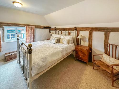 a bedroom with a bed and a chair and a window at Cottage Ixworth in Ixworth