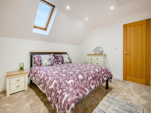 una camera da letto con un letto con un piumone viola e una finestra di Salix 4 - Uk46116 a Wigginton