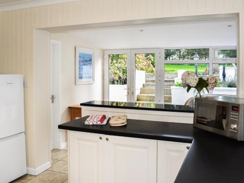 a kitchen with white cabinets and a black counter top at Ffin Yr Afon - Ukc6907 in Towyn