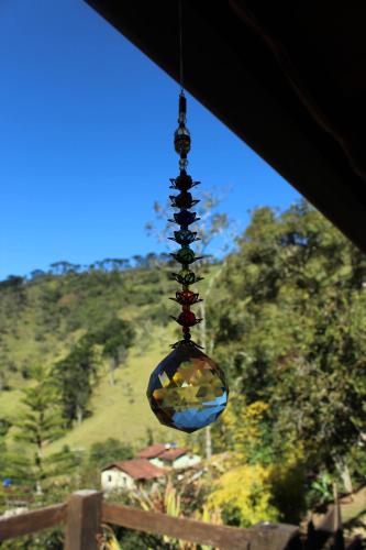 a glass ball hanging from a window with a view at Chalés de Analuz in Visconde De Maua