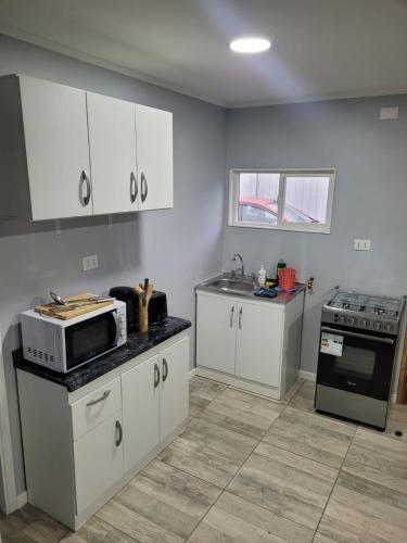 a kitchen with white cabinets and a microwave at Arriendo diario en Valdivia in Valdivia