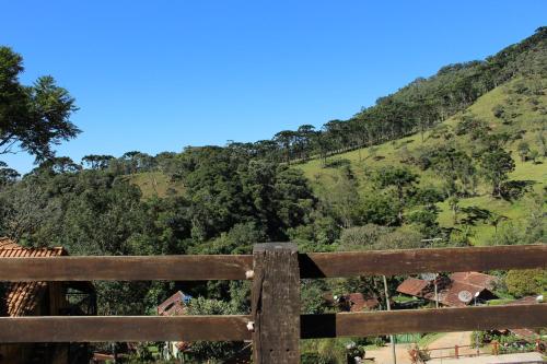 a wooden fence in front of a hill with trees at Chalés de Analuz in Visconde De Maua