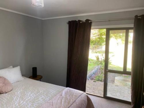 a bedroom with a bed and a sliding glass door at Country Life in Tauranga