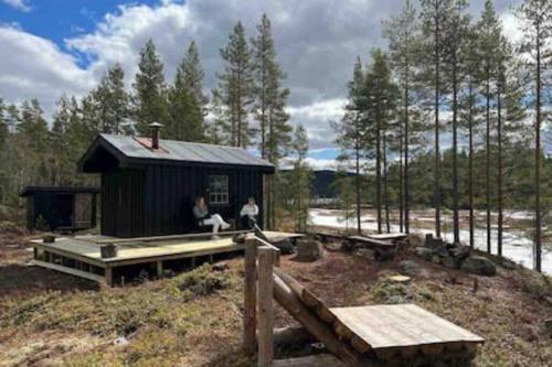 two people sitting on the porch of a small shack at Velkommen til Finnskogen og minihytta Rimbila in Kongsvinger