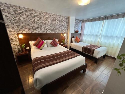 a hotel room with two beds and a stone wall at Hotel Machupicchu Adventure in Machu Picchu