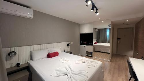 a bedroom with a large white bed and a bathroom at True América apart-hotel in Campos dos Goytacazes