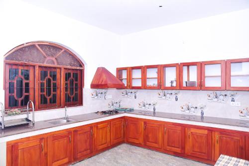 a kitchen with wooden cabinets and a sink and a window at hikka T&O nature villa in Hikkaduwa