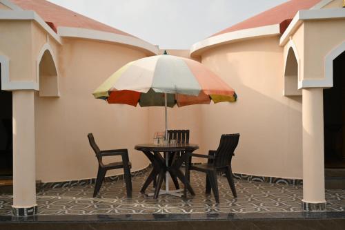 布吉的住宿－Kutch kutir，露台的遮阳伞下的桌椅