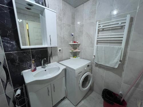 a bathroom with a sink and a washing machine at Troya Suit in Çanakkale