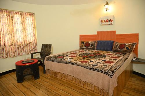 a bedroom with a bed and a chair and a window at Kutch kutir in Bhuj