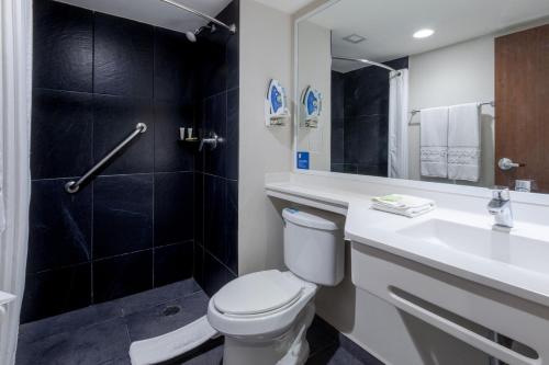 a bathroom with a toilet and a sink and a shower at City Express by Marriott Guadalajara Aeropuerto in Guadalajara