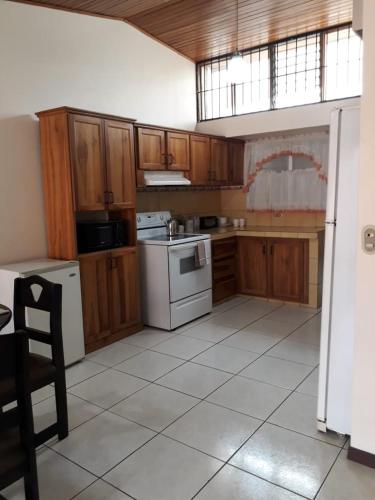una cocina con armarios de madera y electrodomésticos blancos en Kubo Home 4 Bedrooms 5 mins SJO Airport en Alajuela