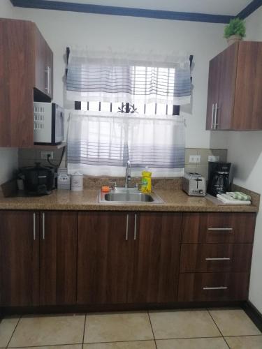 un comptoir de cuisine avec un évier et une fenêtre dans l'établissement Kubo Home 4 Bedrooms 5 mins SJO Airport, à Alajuela