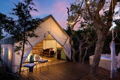 a white tent on a deck next to a tree at Oak Retreat Glamping With Private Hot tub in Luckenbach