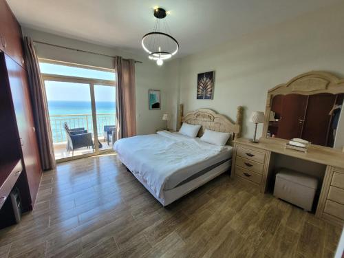 Royal Beach Apartment في King Abdullah Economic City: غرفة نوم مع سرير وإطلالة على المحيط