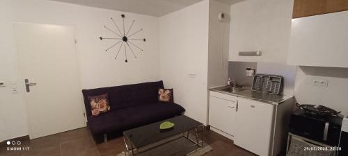 a living room with a couch and a clock on the wall at Appartement meublé in Montpellier