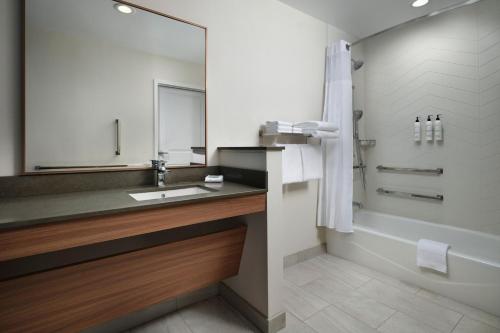 La salle de bains est pourvue d'un lavabo, d'une baignoire et d'un miroir. dans l'établissement Fairfield by Marriott Inn & Suites Barstow, à Barstow