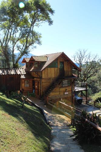a large wooden house with a staircase in front of it at Chalés de Analuz in Visconde De Maua