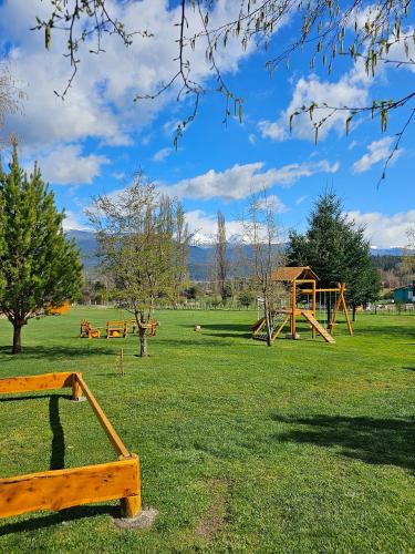 a park with a bunch of playground equipment in the grass at La Yaya - Villa Turismo in El Bolsón
