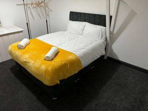 a bed with two pillows and a yellow blanket at Contractors, Groups 4BR 5xDB Close to City free parking sleeps x 10 in Leeds