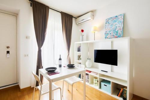 uma sala de estar com uma secretária branca e uma televisão em House Naviglio Grande 15 minutes to duomo em Milão