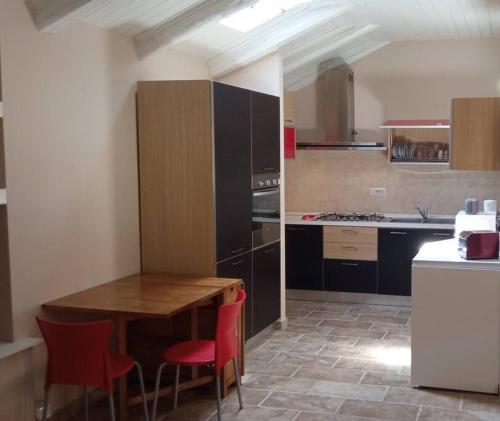 una cucina con tavolo in legno e sedie rosse di appartamento tra Torino e Alba in centro a Sommariva del Bosco